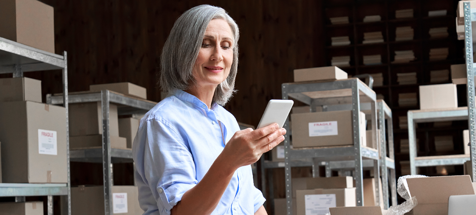 mulher-dentro-de-um-estoque-segurando-celular-para-checar-dados-sobre-a-gestão-de-riscos-no-varejo