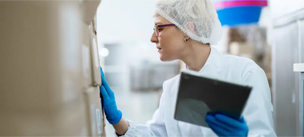 mulher-usando-touca-e-segurando-tablet-conferindo-o-romaneio-da-carga