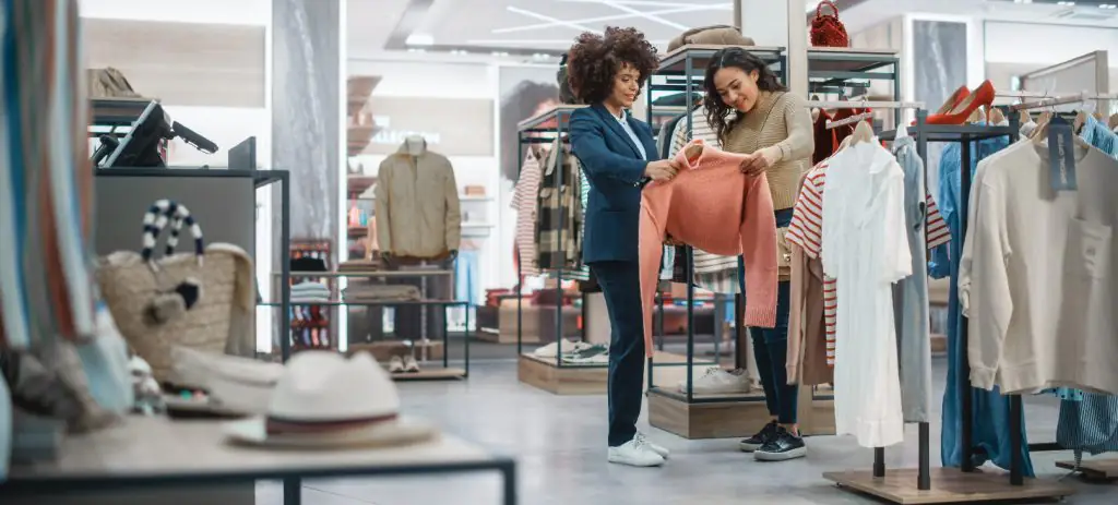 duas-mulheres-segurando-um-casaco-em-uma-loja-gerenciando-estoque-e-realizando-um-planejamento-estratégico-no-varejo